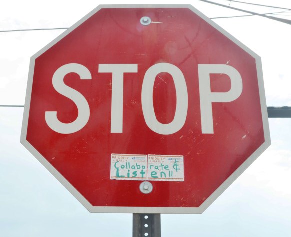 stop sign to which someone has added a sticker that says collaborate and listen