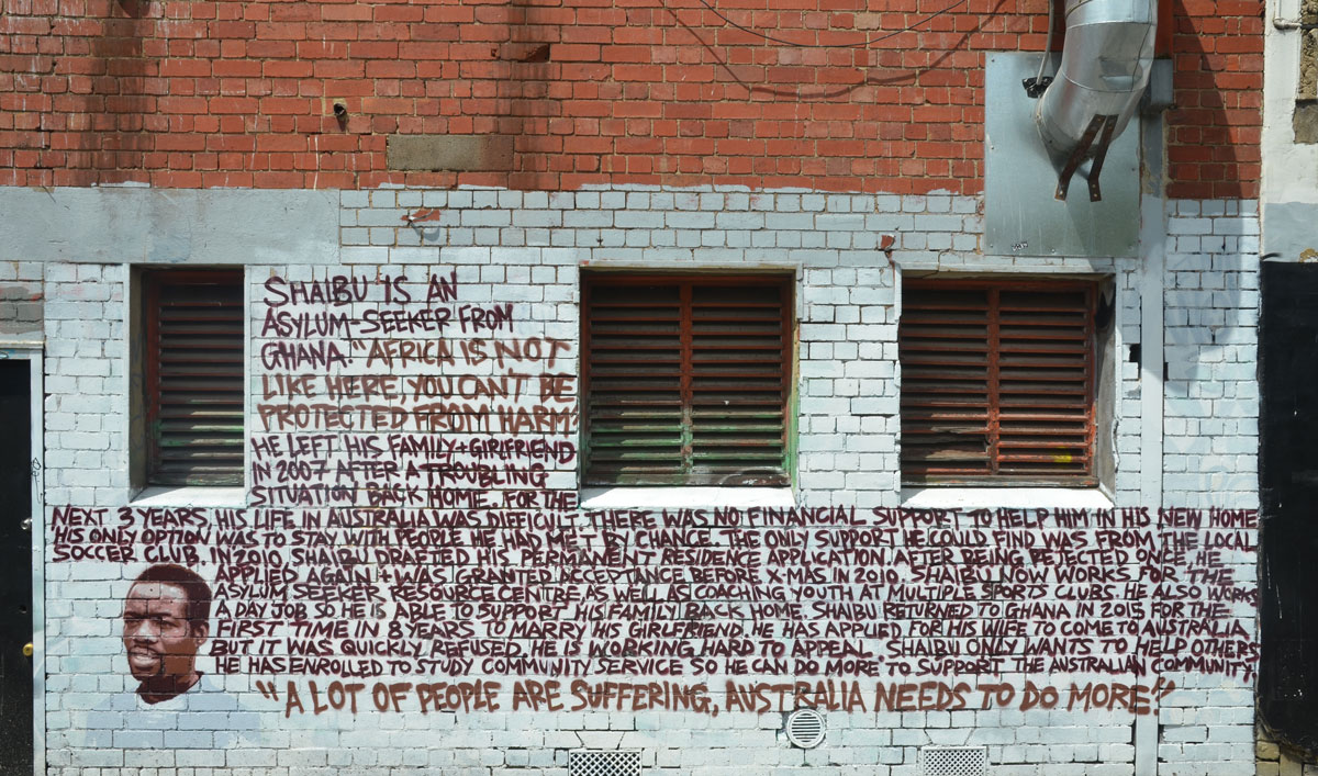 A lot of words written on a wall. Brown letters, white brick wall. 