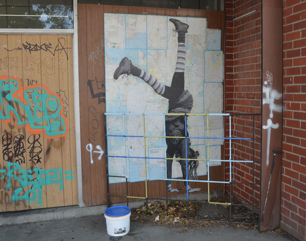 paste up by Larissa McFarlane of a life sized person doing a handstand while wearing striped socks