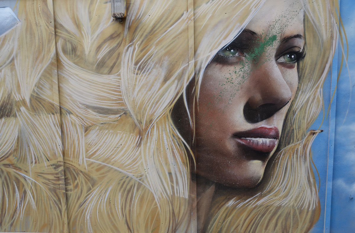realistic painting of a woman's face in profile on a wall, long blond hair
