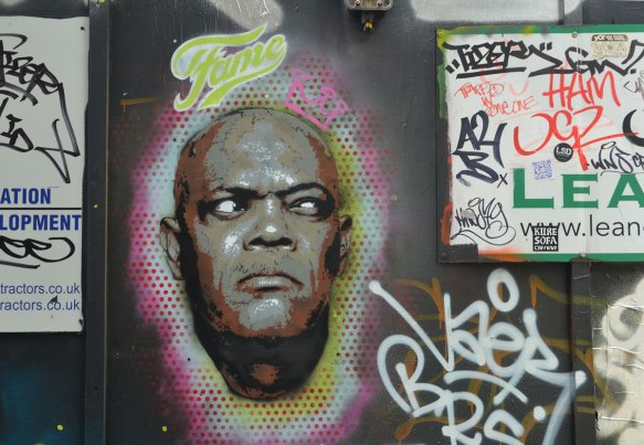 street art portrait of a black man's face, with the word fame written above it and a small pink crown drawn on the side of his head