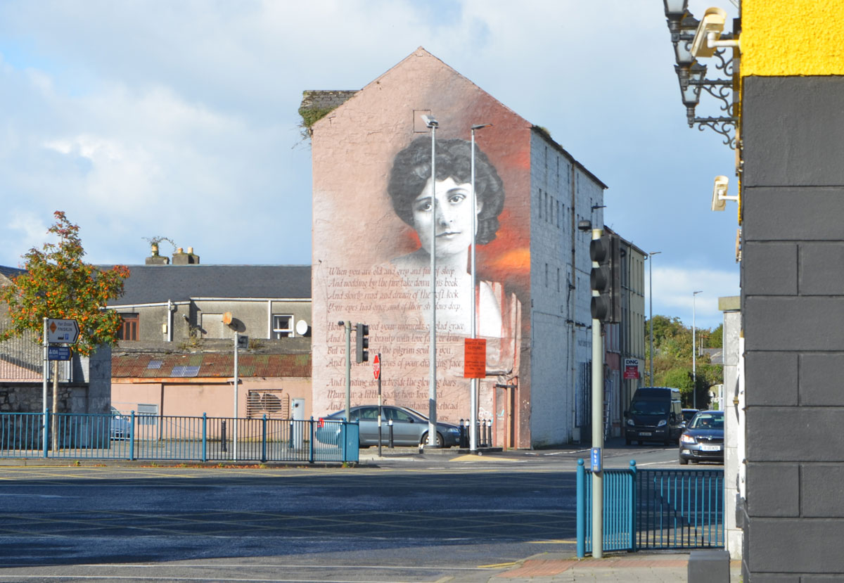 a mural covers the side of a multistorey building, a woman's head and lines of poetry, When you are old by William Butler Yeats. 