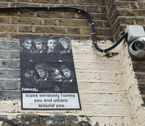 graffiti and street art on fashion street in shoreditch east london, a poster with black and white pictures of mens heads with the words Icons seriously harms you and others around you