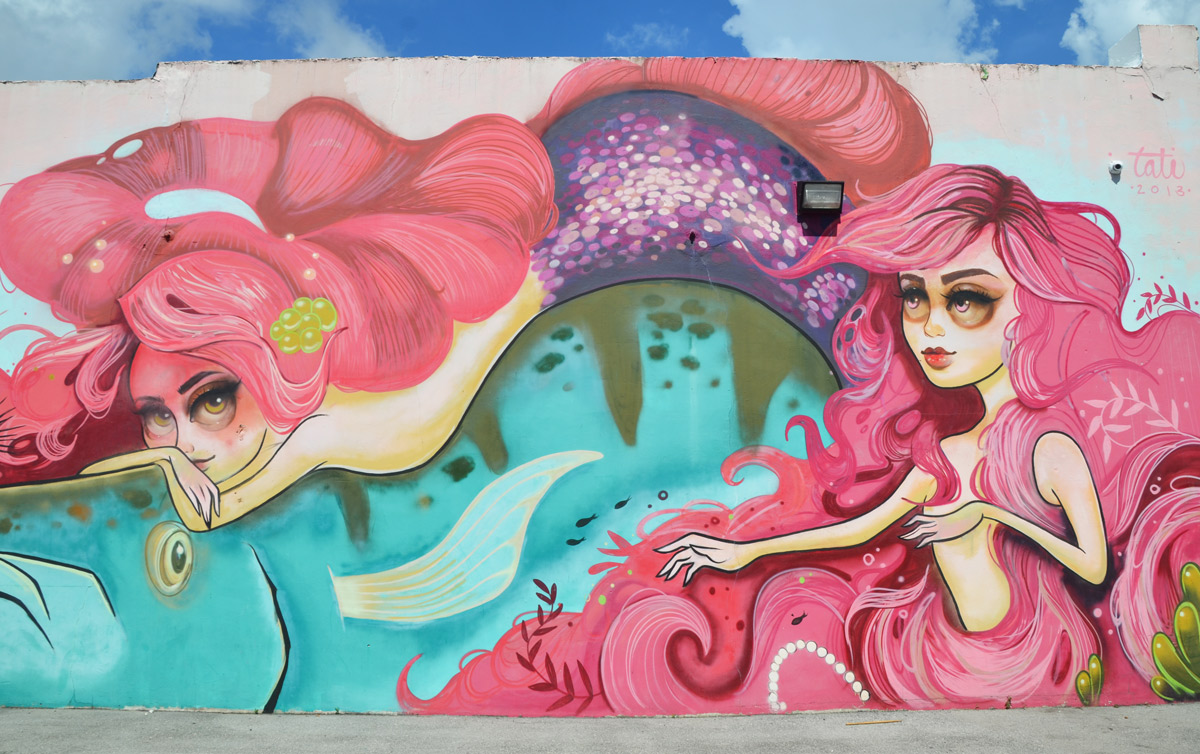 part of a larger mural by Tati Suarez, @tatunga, of mermaids - mermaids with long pink hair and purple fins swimming in blue water