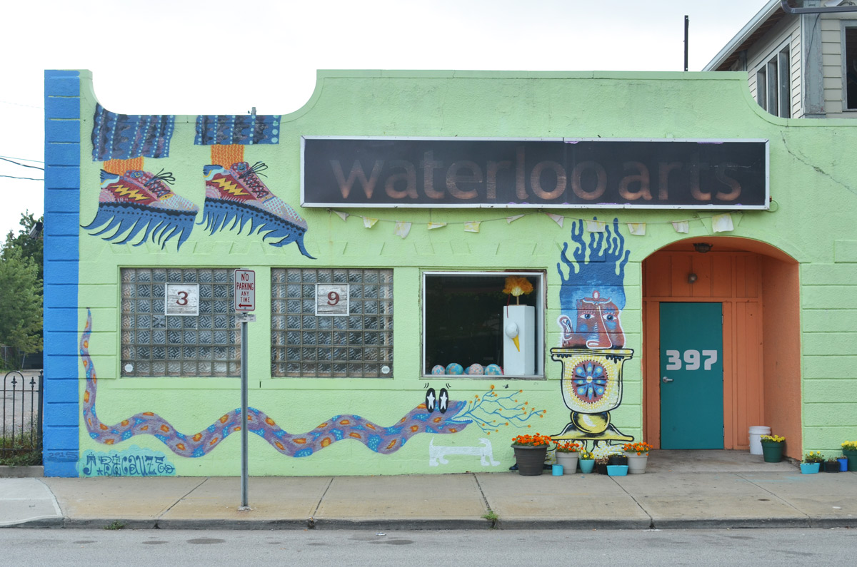 the front of the Waterloo Arts building in Cleveland, painted in light green with other designs, such as a long snake. three windows, two are closed and one is open 