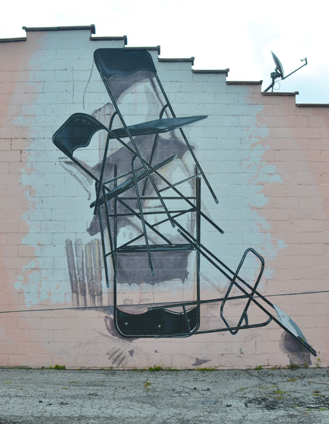 on the side of building in CLeveland, a mural of a stack of foldable chairs, open, disorderly pile, not neatly piled, 