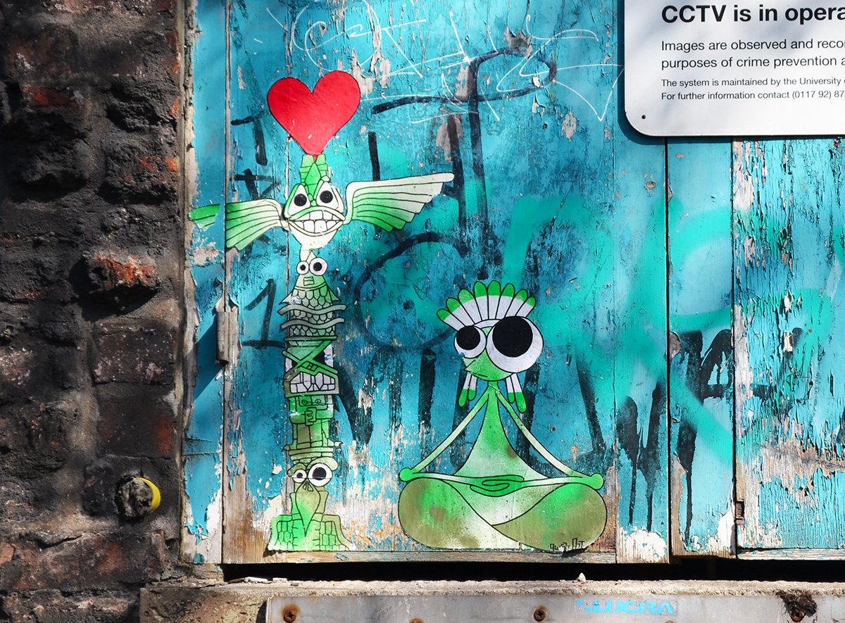 two little green andwhite characters on a blue wall, a red heart is above the head of a tall skinny standing creature while the other is sitting crossed legged beside him 