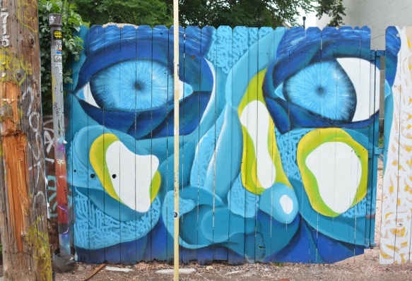 gate, painted with mural, large blue face, eyes, nose and cheeks, light green highlights, 