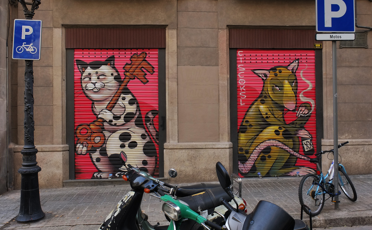 motorcycle in front of two doors with murals. on the left is a cat and on the right is a greenish coloured mouse. both animals fill the door. 
