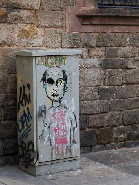 metal utility box on a sidewalk beside a stone wall, drawing of the upper part of a man, in black line drawing. 