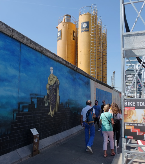 people walking past part of a mural on Berlin Wall, Eastside gallery