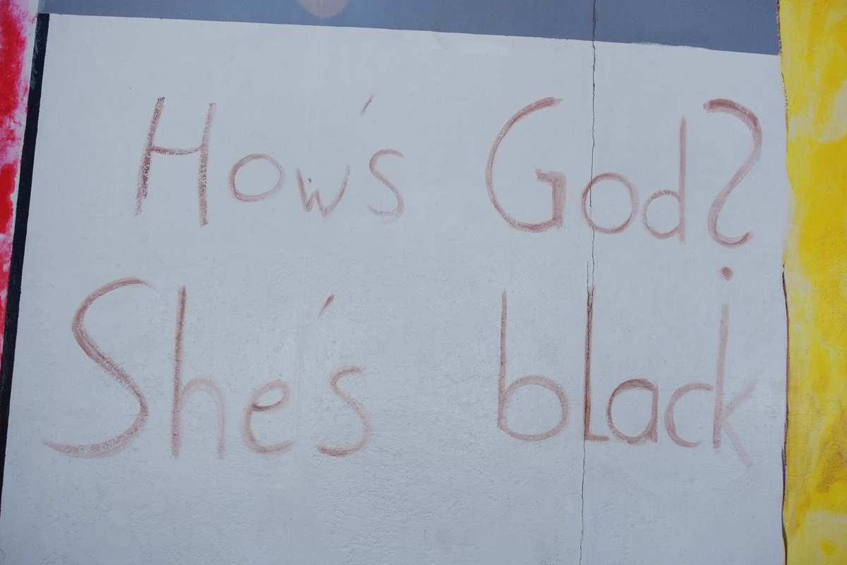 writeen words, brown on white, large letters, How's God she's black 