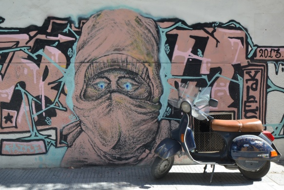 motorbike parked in front of a mural of a person with head covering and veil 
