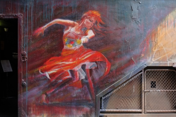 adnate maural of a woman dancing, wearing a red skirt and with red hair, swirling skirt, arm up as she dances 