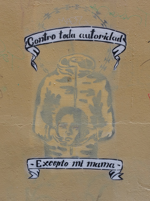 words on top and below a headless figure holding the head of a woman in its hands, words say contro toda autoridad excepto mi mama which is Spanish for I defy all authority except my mother 