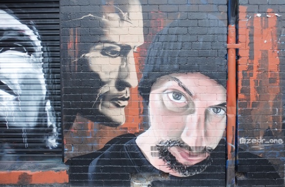 street art piece by zedr_one of two men's faces, one in profile, and the other more straight on. The second, is wearing a black toque hat and has the start of a beard and a moustache. 
