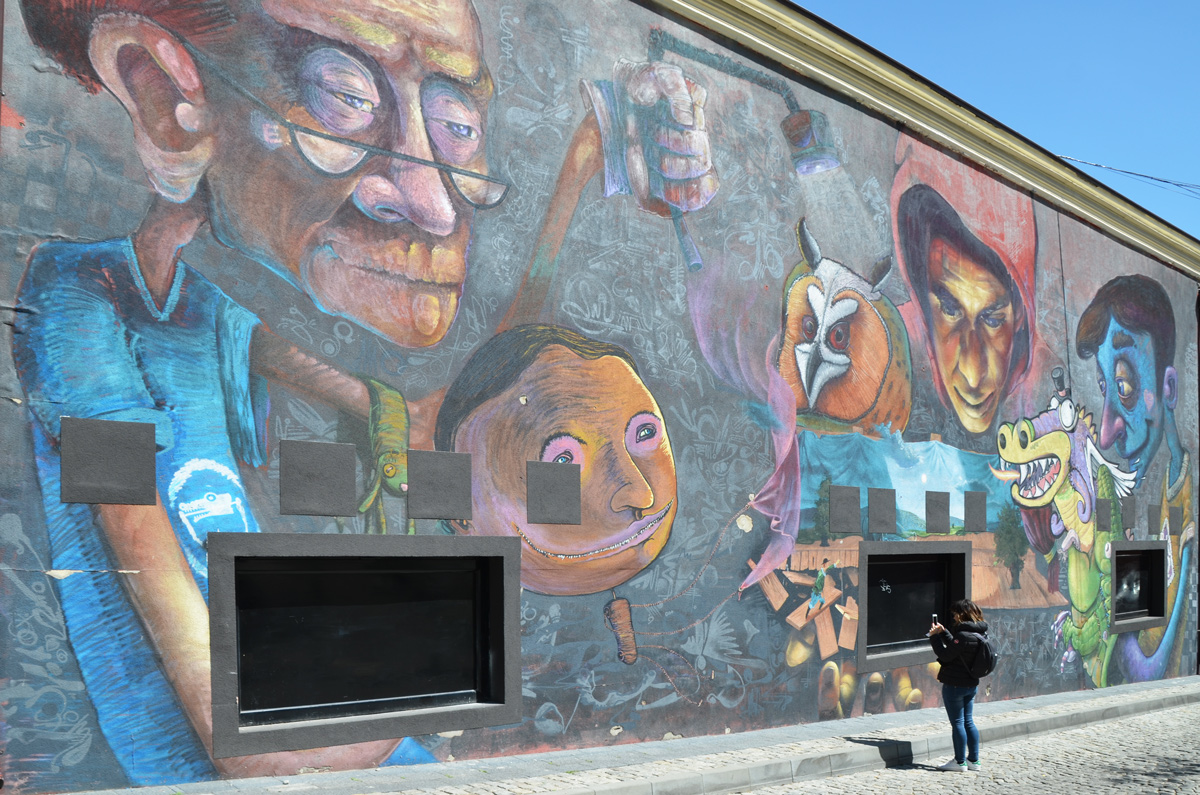 a woman is taking a photo of a large mural by Dimitar Mehandjiiski a k a stern in Plovdiv, external wall, puppets people