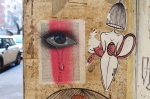 eye and red streak painted on a page of a book, now is graffiti, beside a pasteup of a woman with a birdcage for a head