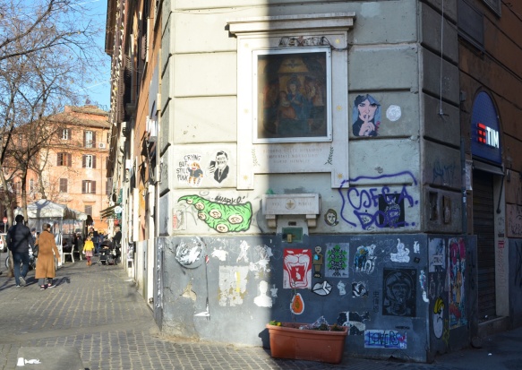 wall in trastevere rome with graffiti on it as well as a picture of the virgin mary . 