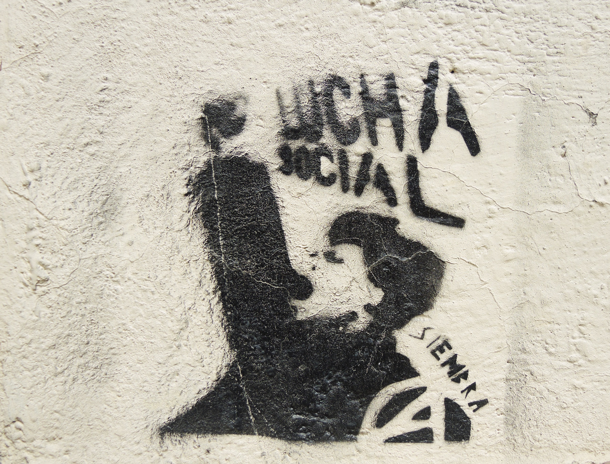 graffiti stencil in black of a man with fist upraised and open mouth, words lucha social