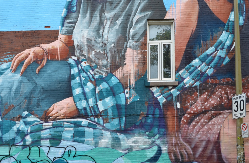 Close up of mural by Fintan Magee in Montreal, by small window in building, hands of women plus their blue and white scarves