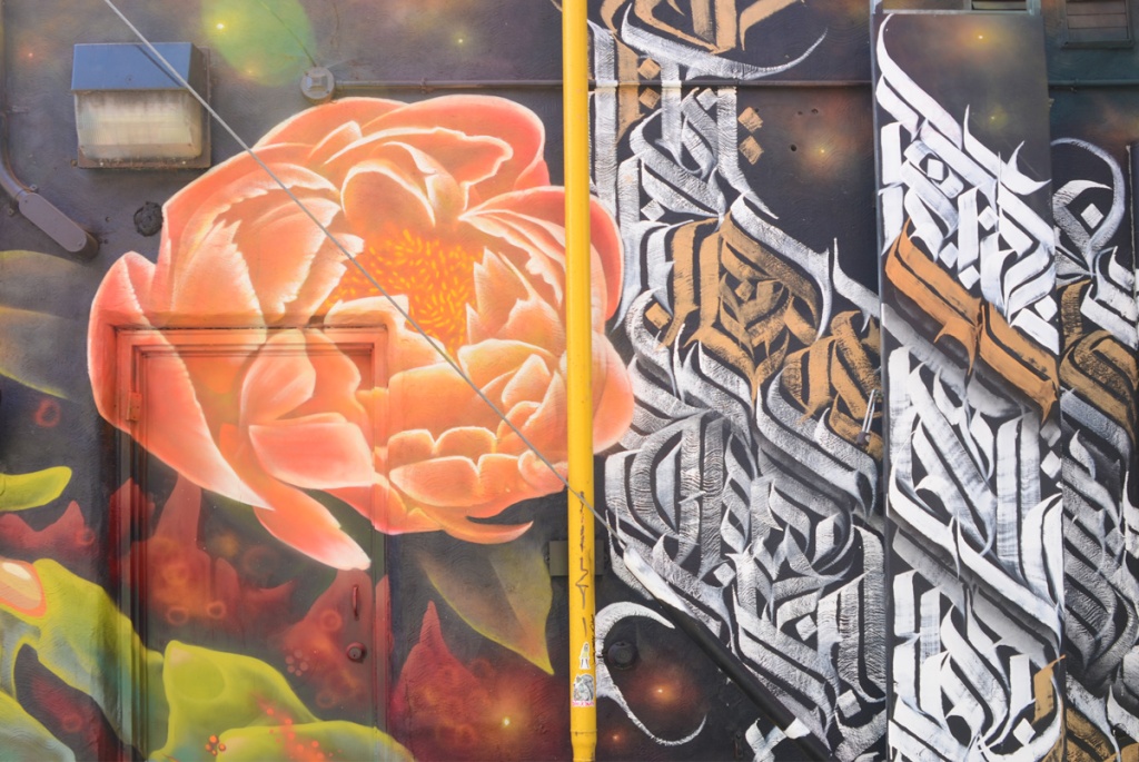 contributions by bacon, a flower, and kreecha, calligraphy designs in white and gold, on a mural