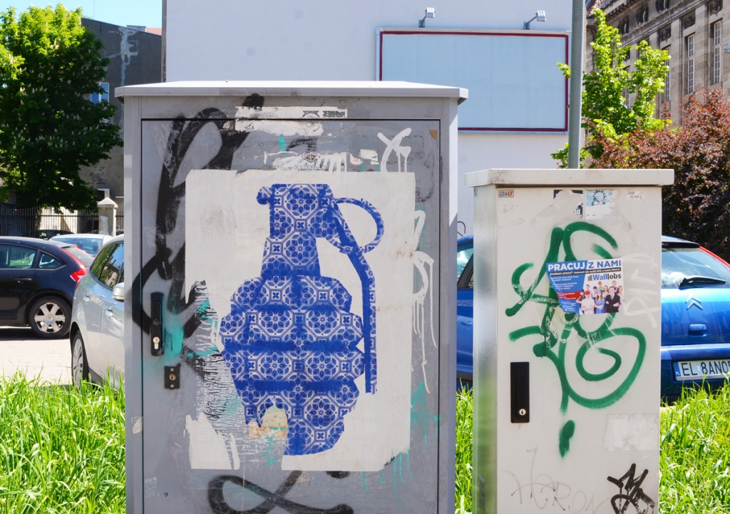 paper paste up on a metal sidewalk box, a large hand grenade made of repeating blue and white geometric pattern