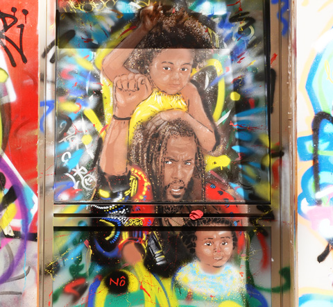 street art painting in Paris of a black man in dreadlocks with two girls, one on his shoulders, the other in front of him