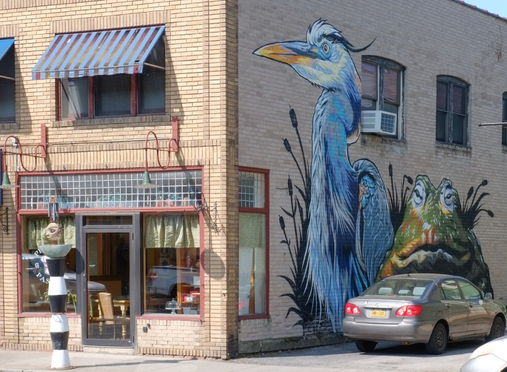 on the side of a store, a large mural of a stork and a green frog