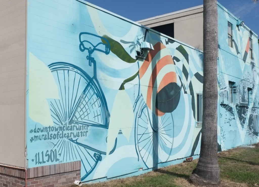 bike, in a mural by illsol, clearwater, palm tree trunk in front of it, muralsofclearwater,