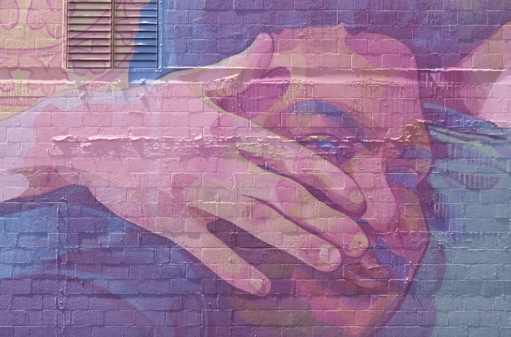 a large hand over a man's face, part of a large mural by gleo