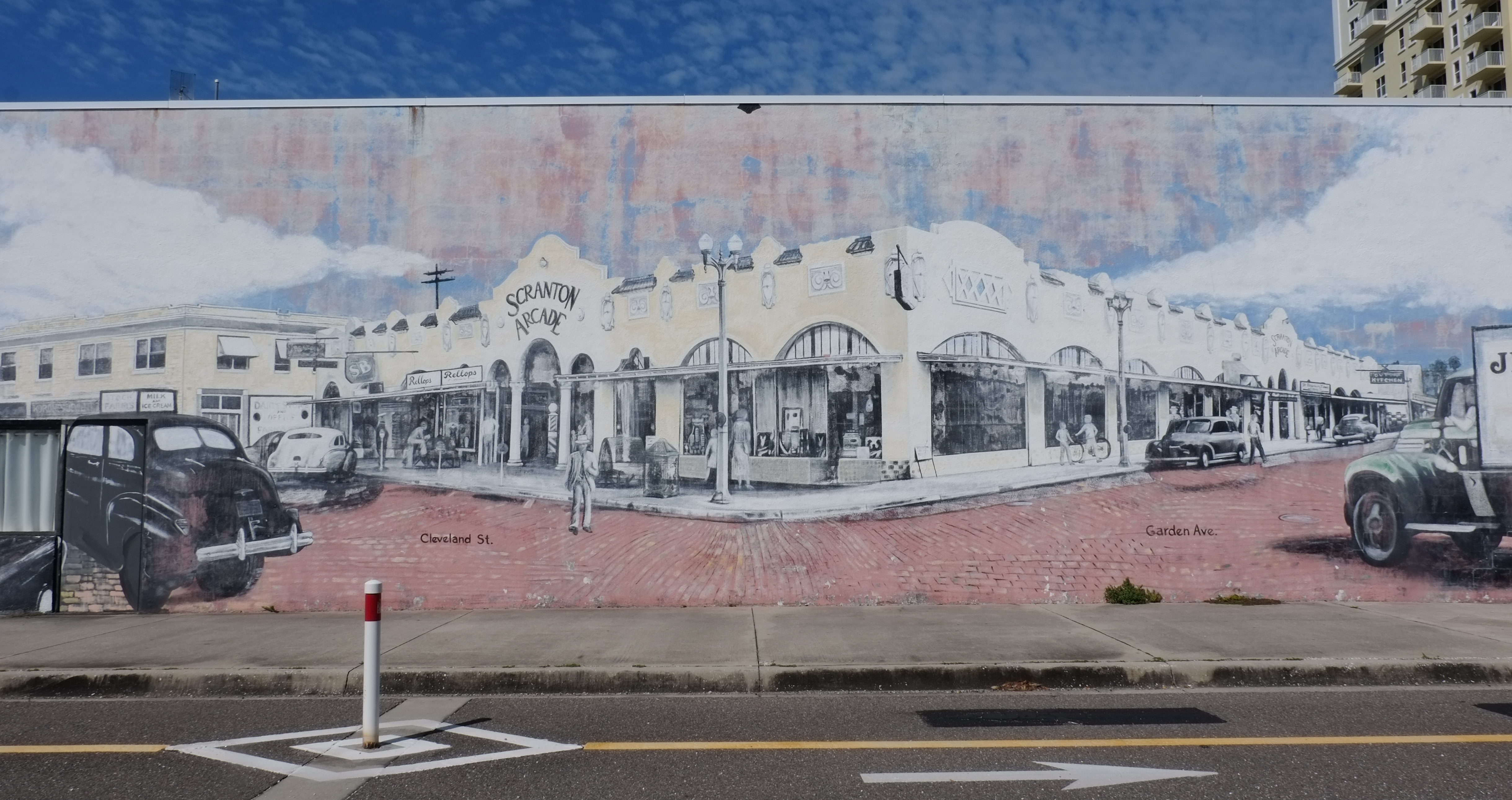 mural that looks like an old photograph of the intersection of Garden Ave and Cleveland St in Clearwater, old cars and trucks, Scranton Arcade, stores, restaurant, downtown