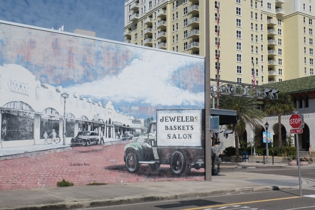 right hand side of a mural showing part of clearwater in the past, old truck with sign on side that says Jewelers Baskets Salon, 
