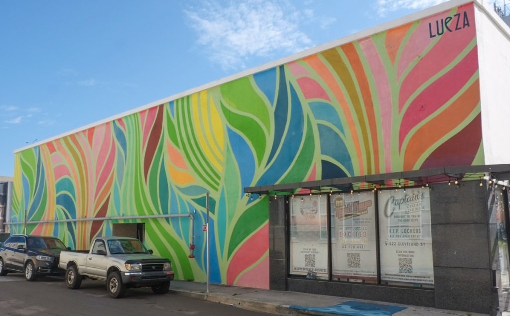 swirls of colours, a mural by lueza, shades of greens that look like leaves, some pinks and oranges too