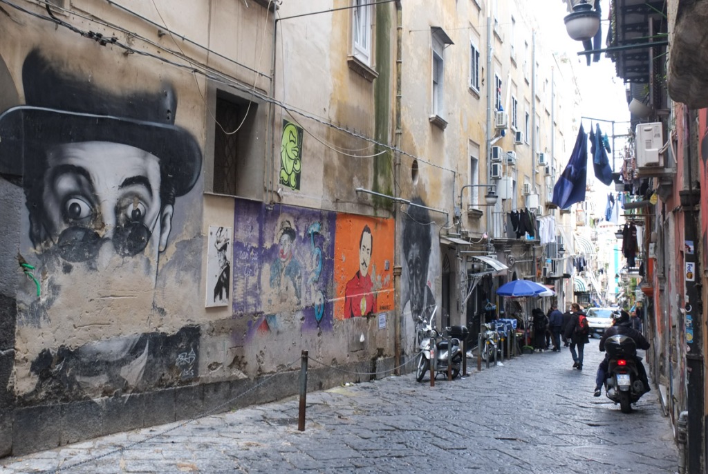 alley in old city part of Naples, stone pavement, motorbike, old murals on the wall, Toto Alley, Vico Toto, portraits of Antonio de Curtis, an actor from the 1950s and 1960s, 
