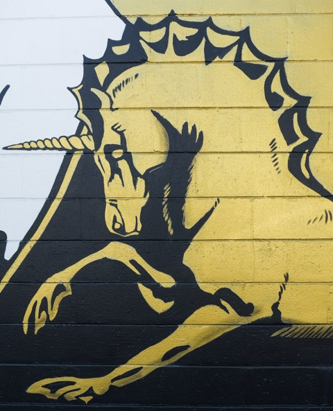 part of a mural, a gold coloured unicorn with one horn in middle of head